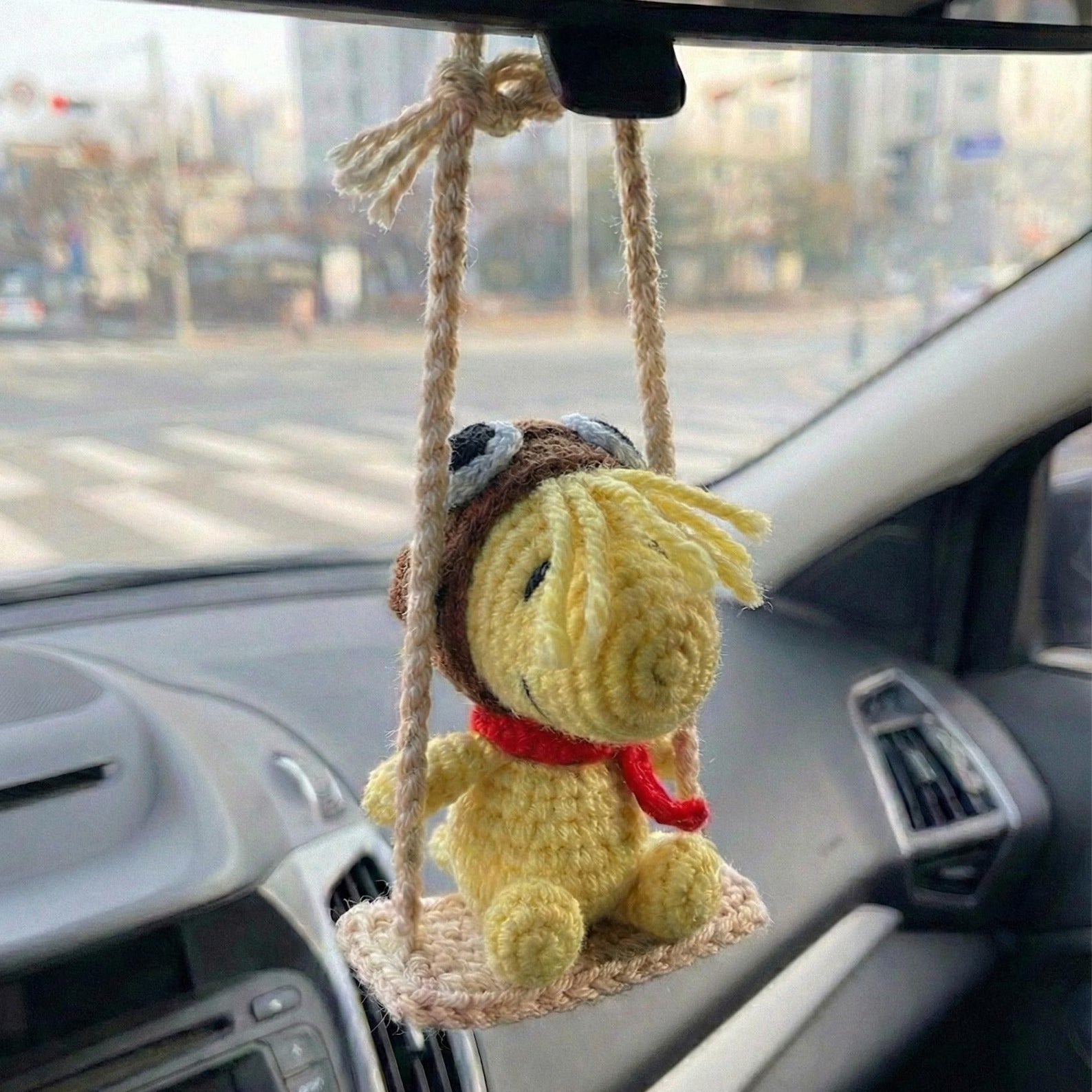 Crocheted character hanging from a car's rearview mirror